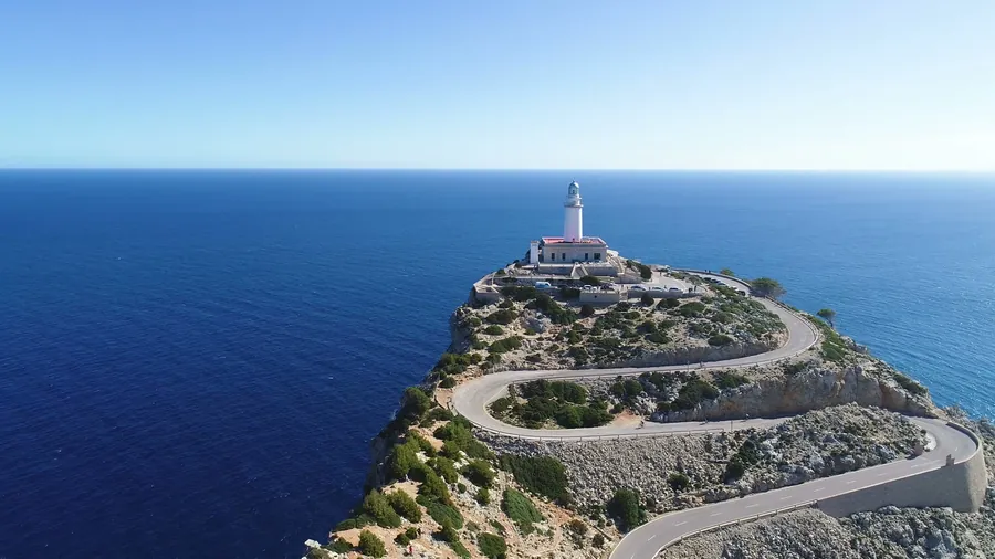 Die kurvige Straße zum Leuchtturm am Cap de Formentor auf Mallorca, aus der Luft fotografiert, rundherum das tiefblaue Meer